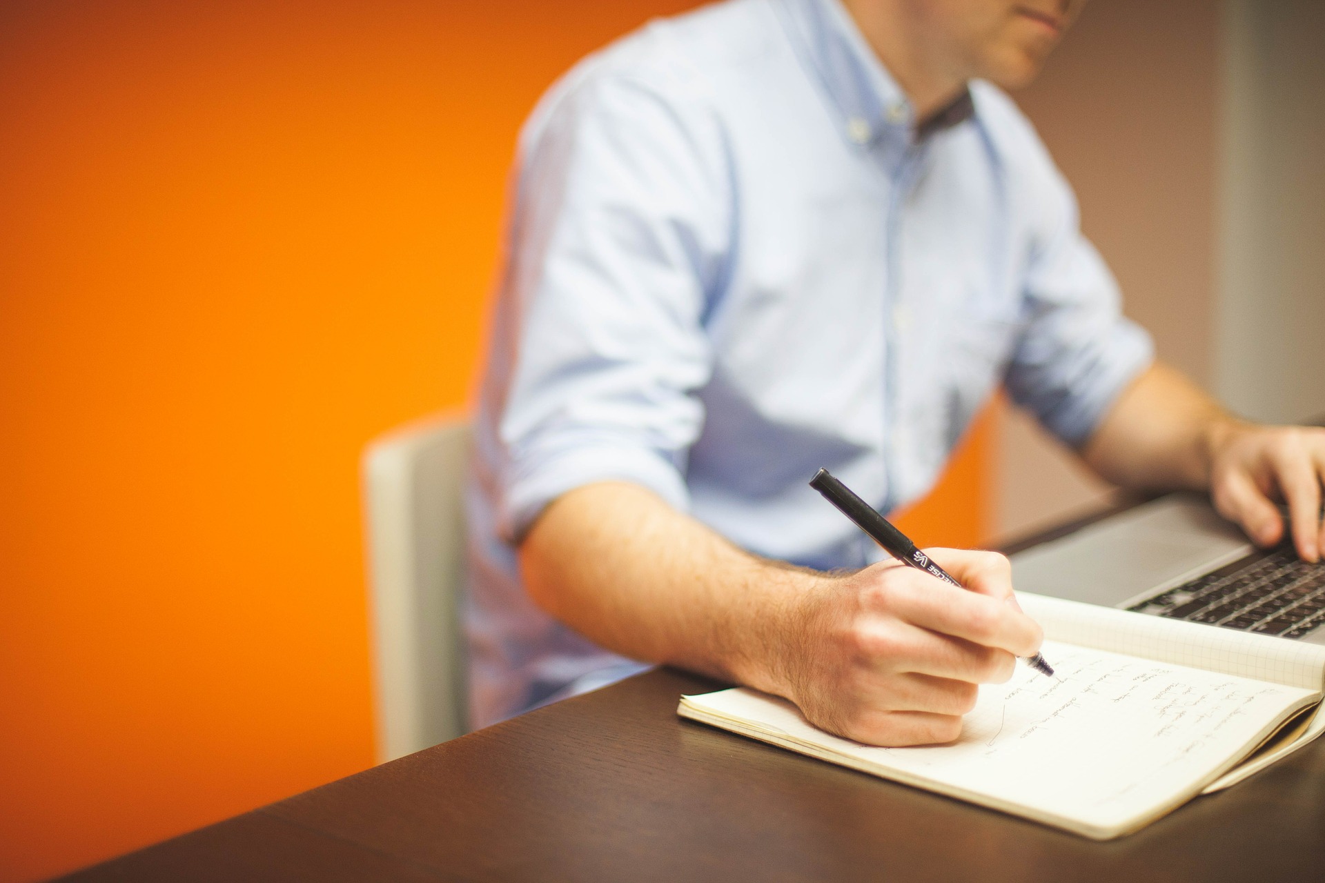 man using a laptop and writing