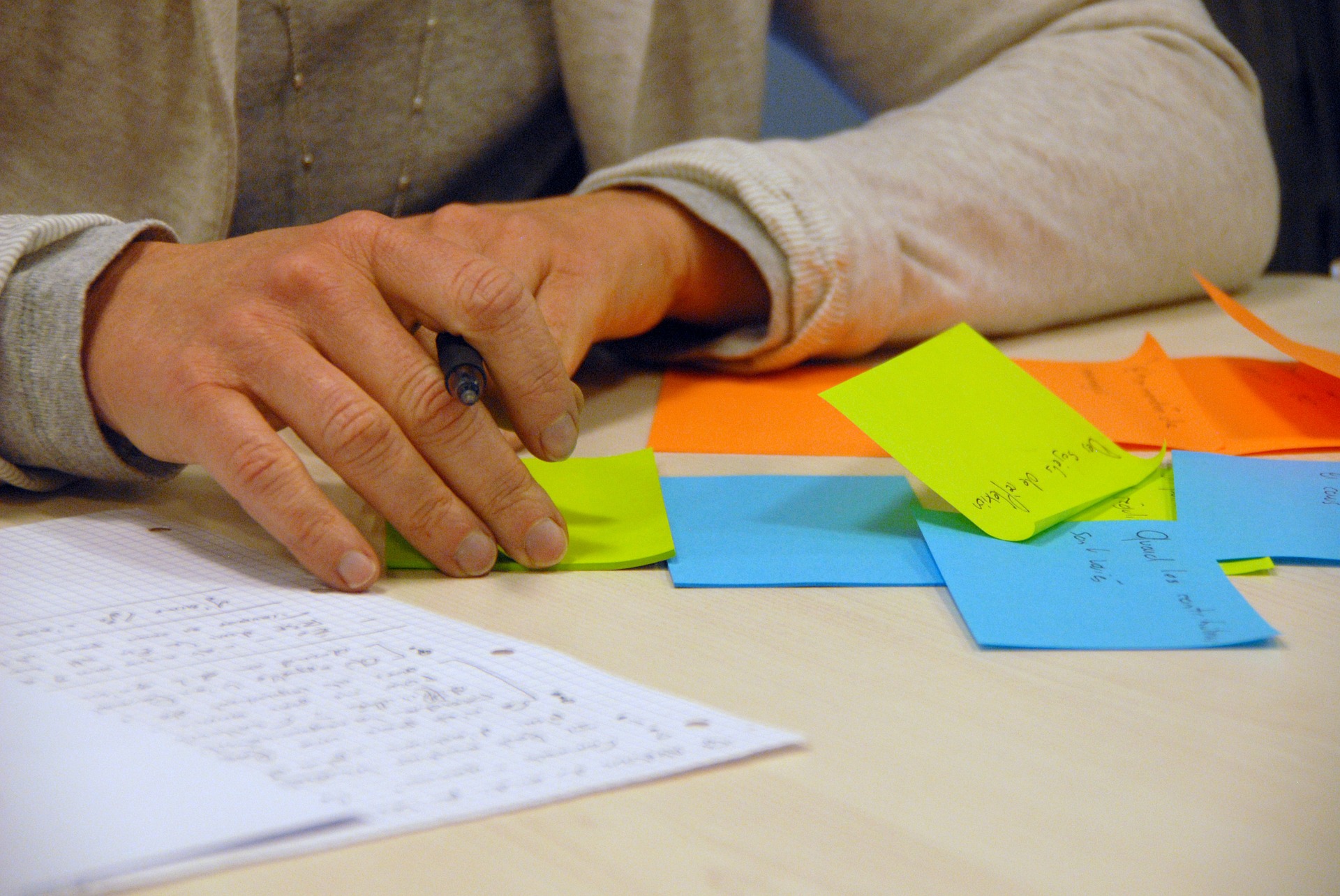 Una persona escribiendo en muchas notas adhesivas de diferentes colores.
