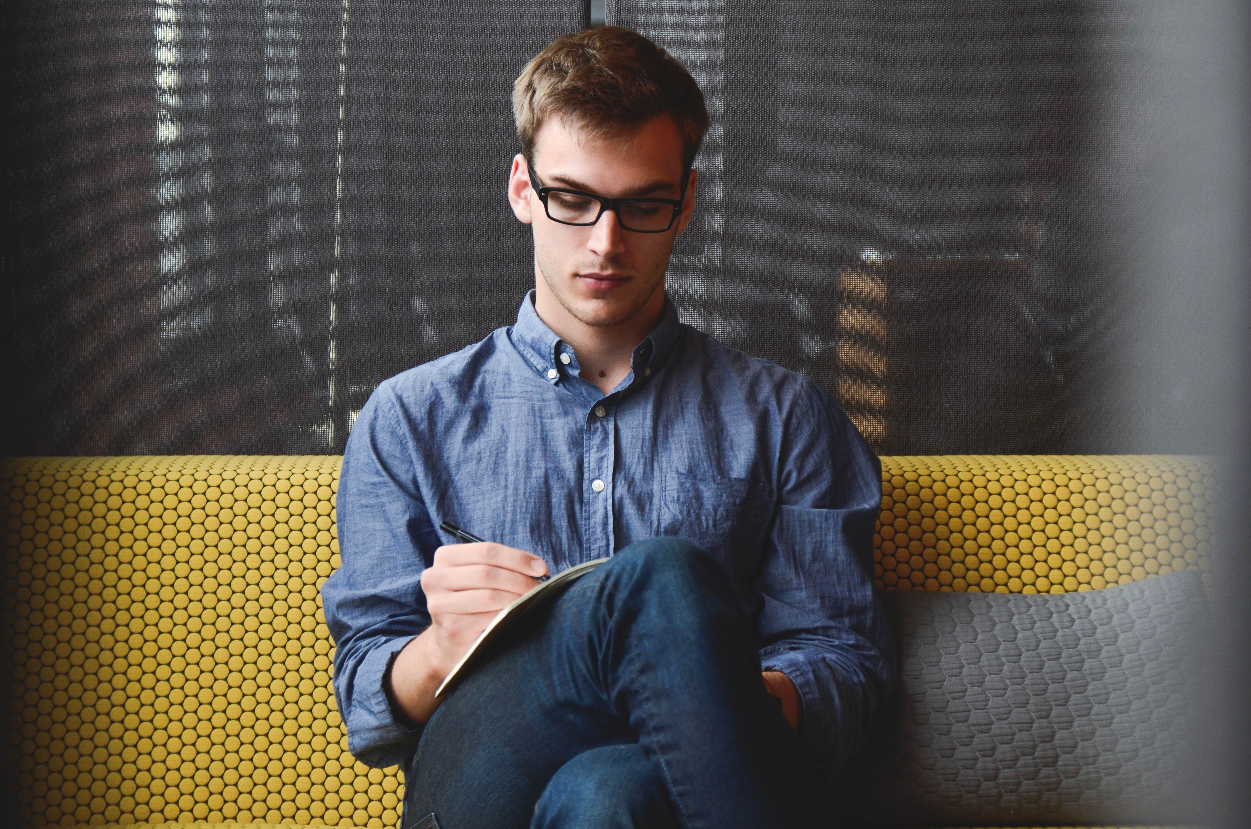 A man sitting on a couch writing