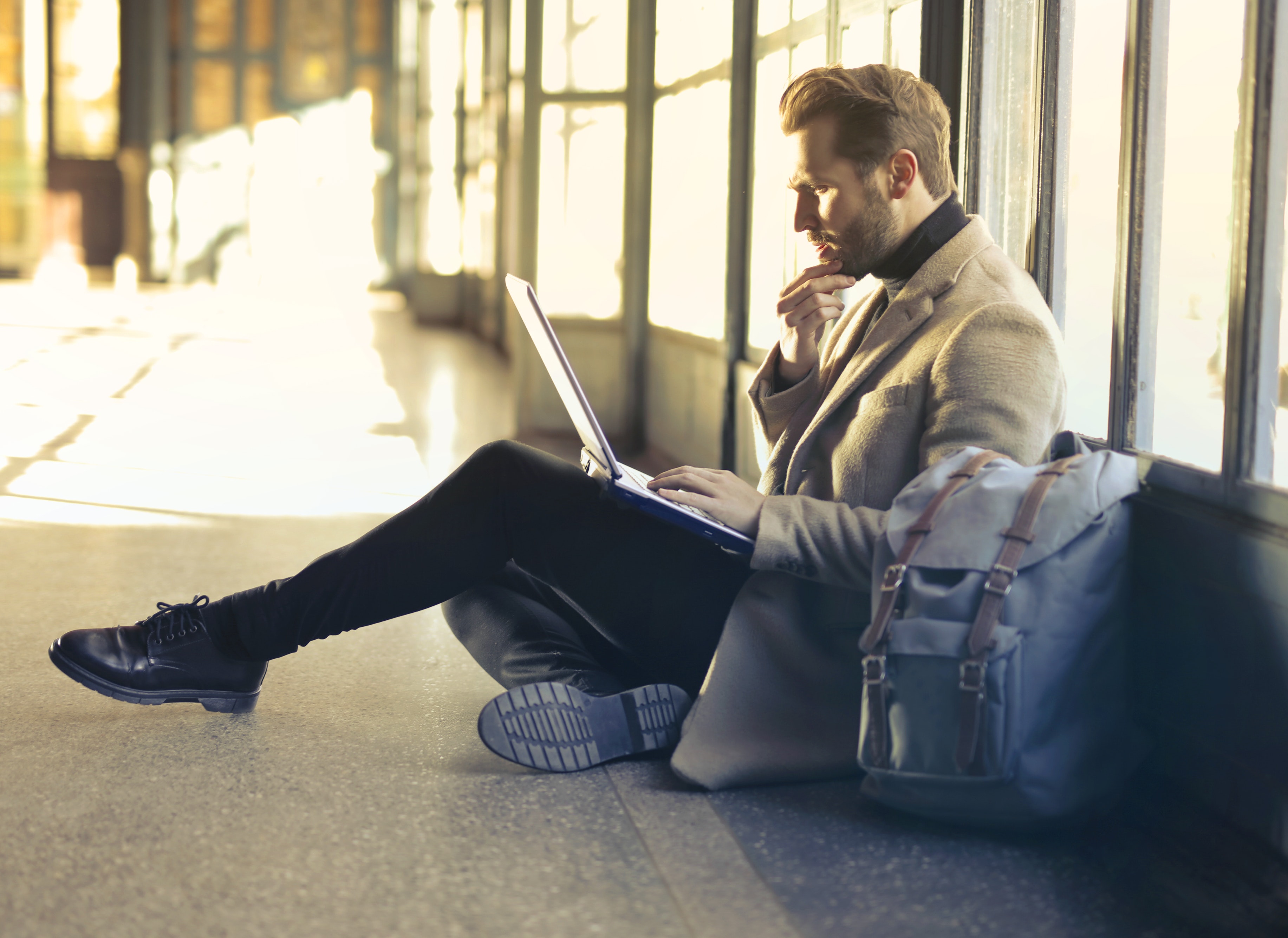 A man sitting and thinking while looking at his laptop open.