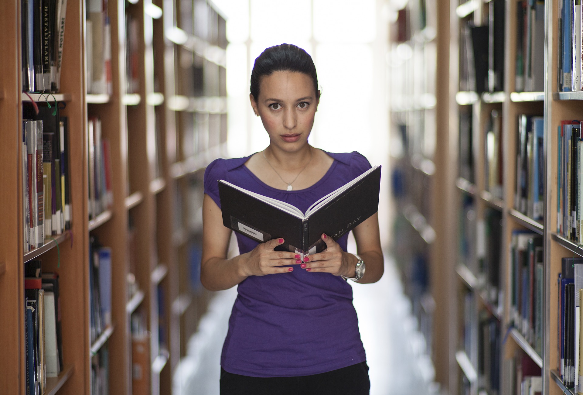 A woman reading a book in a library.