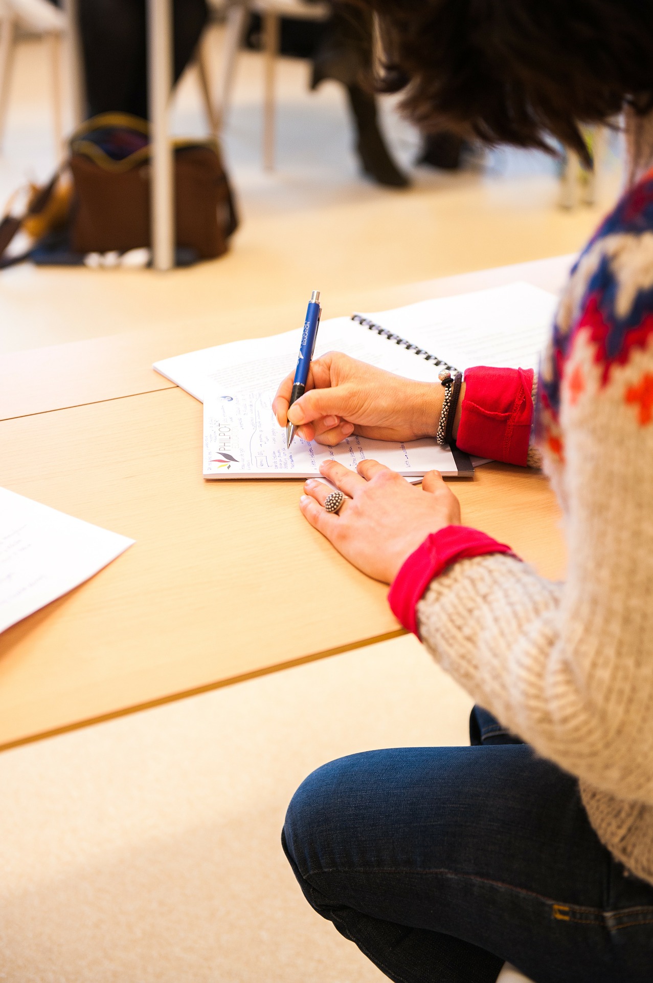 A woman sitting at a desk writing in a notebook