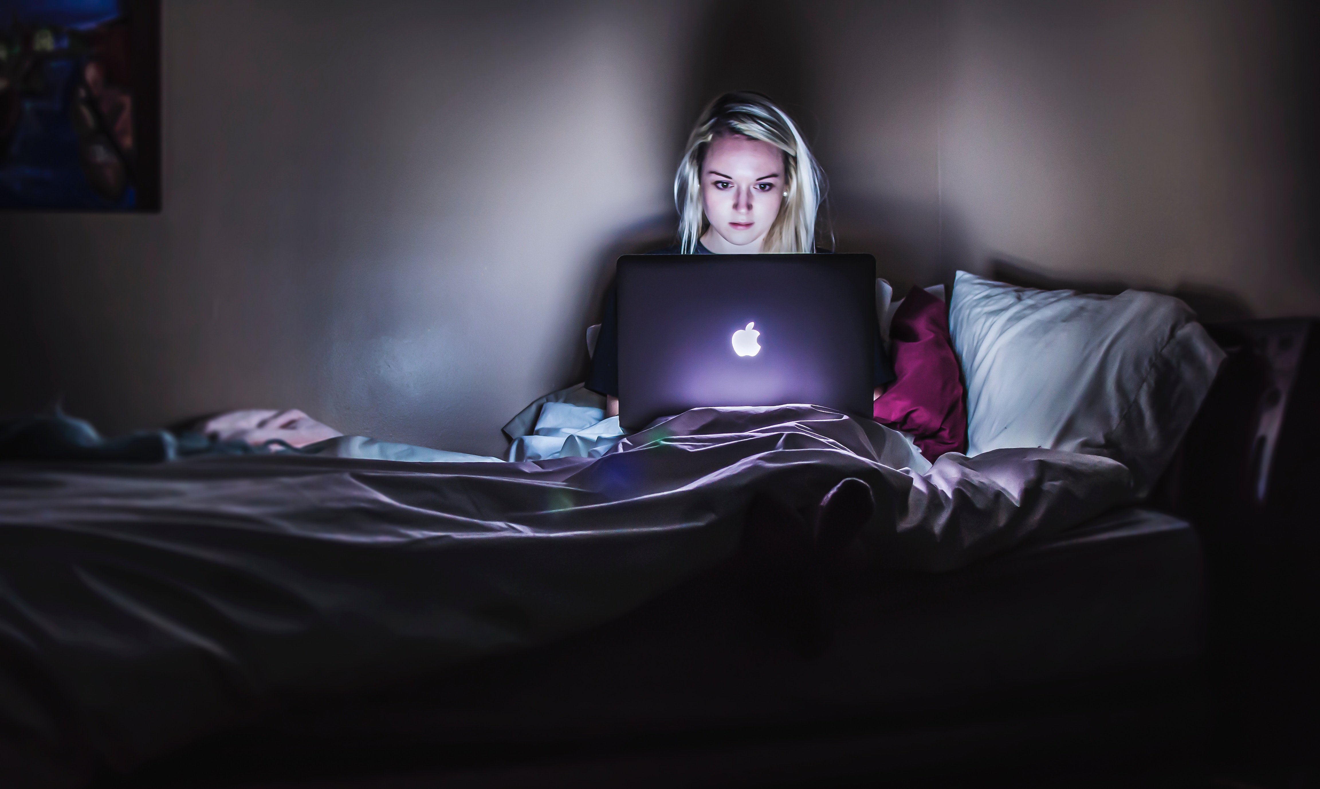 A woman watching a scary movie on a laptop.