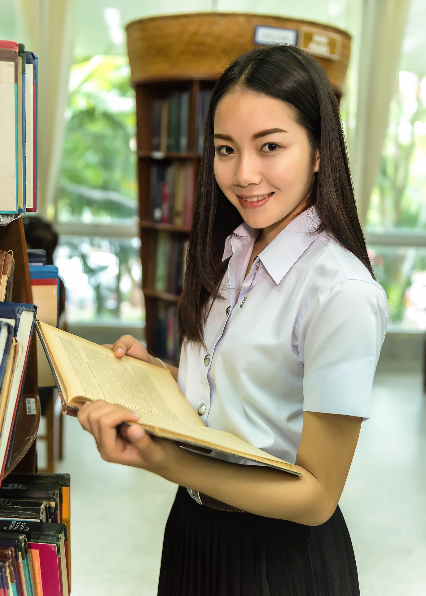 A woman at a library holding a book open learning about rhetorical styles.