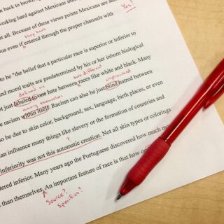 A red pen being used to grade an essay.