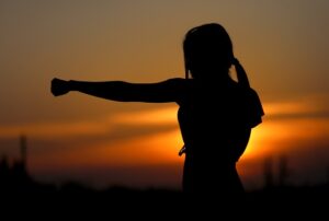 A woman practices karate at sunset.