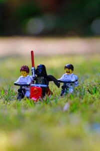 A Lego version of Darth Vader rides through a field with some scared storm troopers.