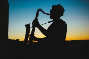 A man plays a saxophone at sunset.